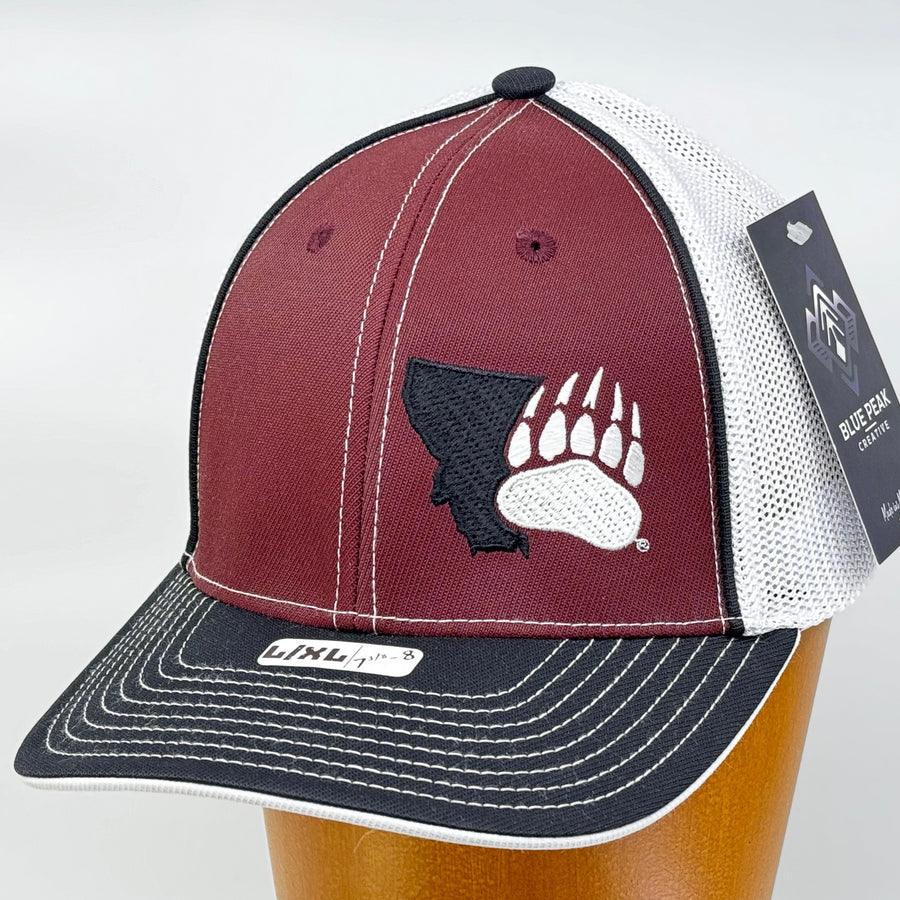Blue Peak Creative's maroon, black, and white Trucker Pacflex Hat embroidered with the Montana Grizzlies Paw design in black and white (3/4 view)