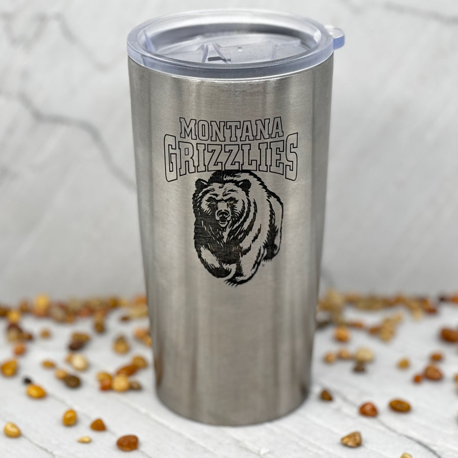 Blue Peak Creative's Silver 24oz Stainless Steel Tumbler decorated with the Montana Grizzlies Charging Bear design in black (front)