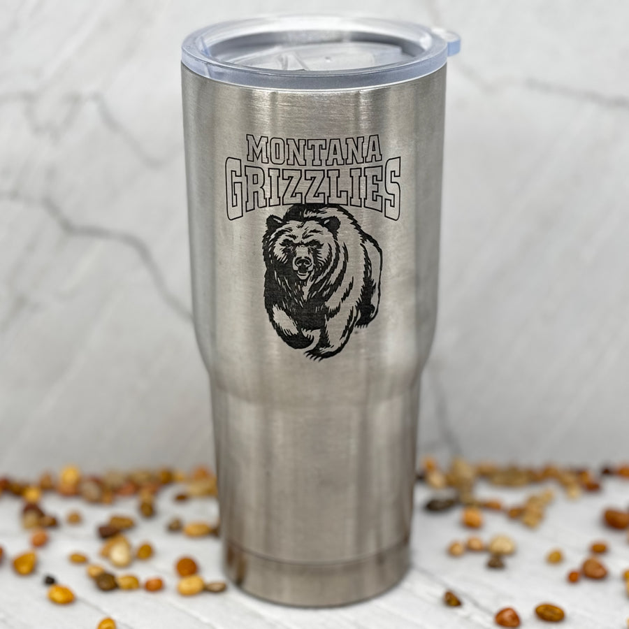 Blue Peak Creative's Silver 22oz Stainless Steel Tumbler decorated with the Montana Grizzlies Charging Bear design in black (front)