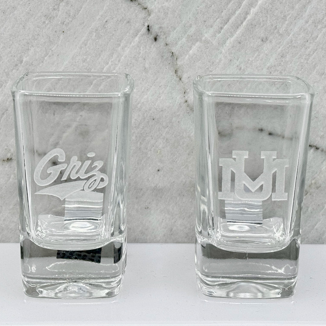 Blue Peaks Creative University of MT etched square shot glasses, two versions: UM logo and Griz Script