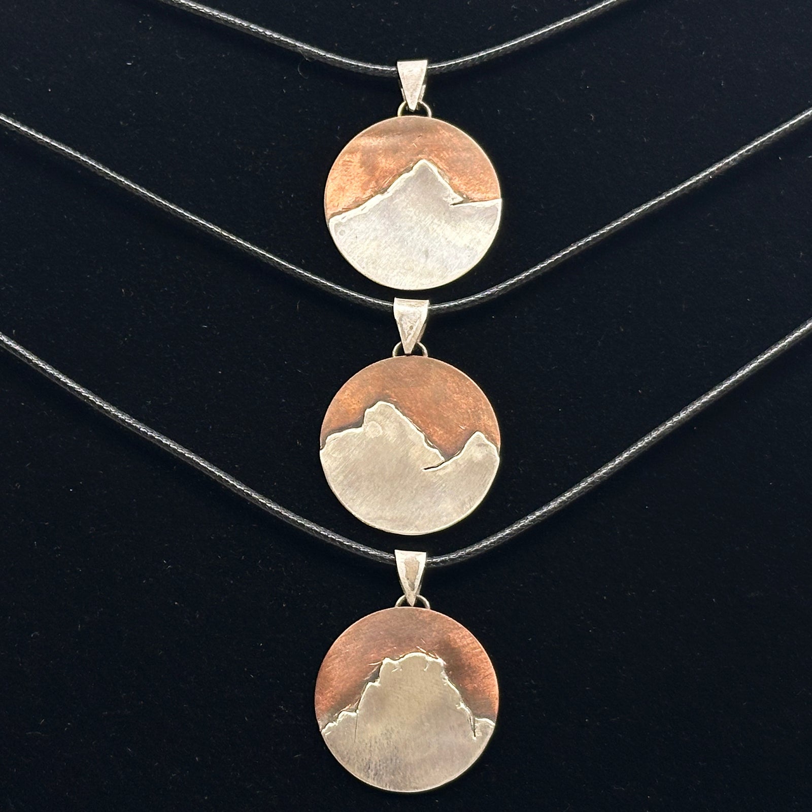 Three Bull & Bear's Copper and .925 Sterling Silver Montana Mountain Pendants, featuring various peaks in Montana, on black cords