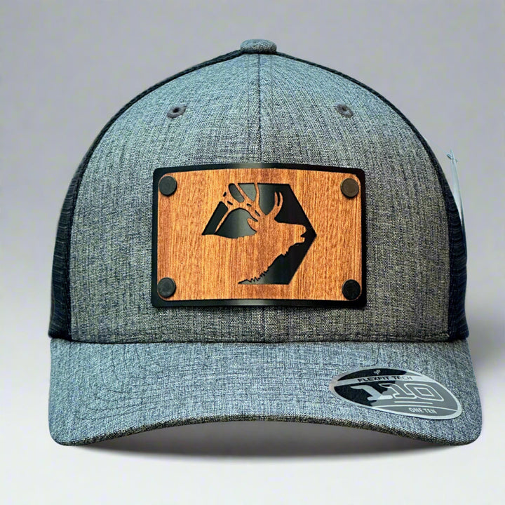 A grey and black flex fit trucker hat with a elk wood patch in mahogany.