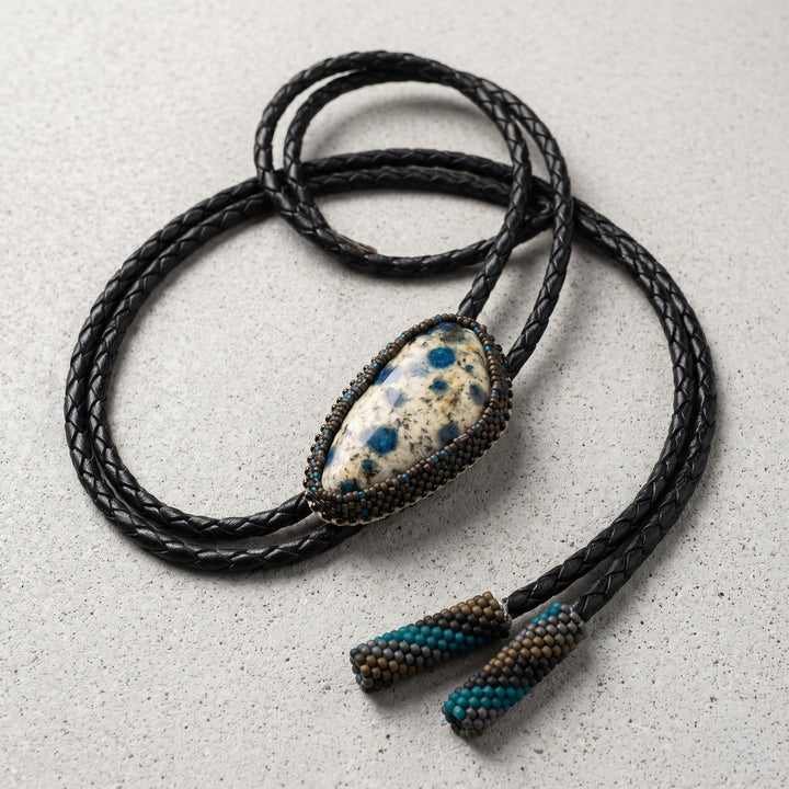 Black braided leather necklace with a stone pendant on a light gray surface