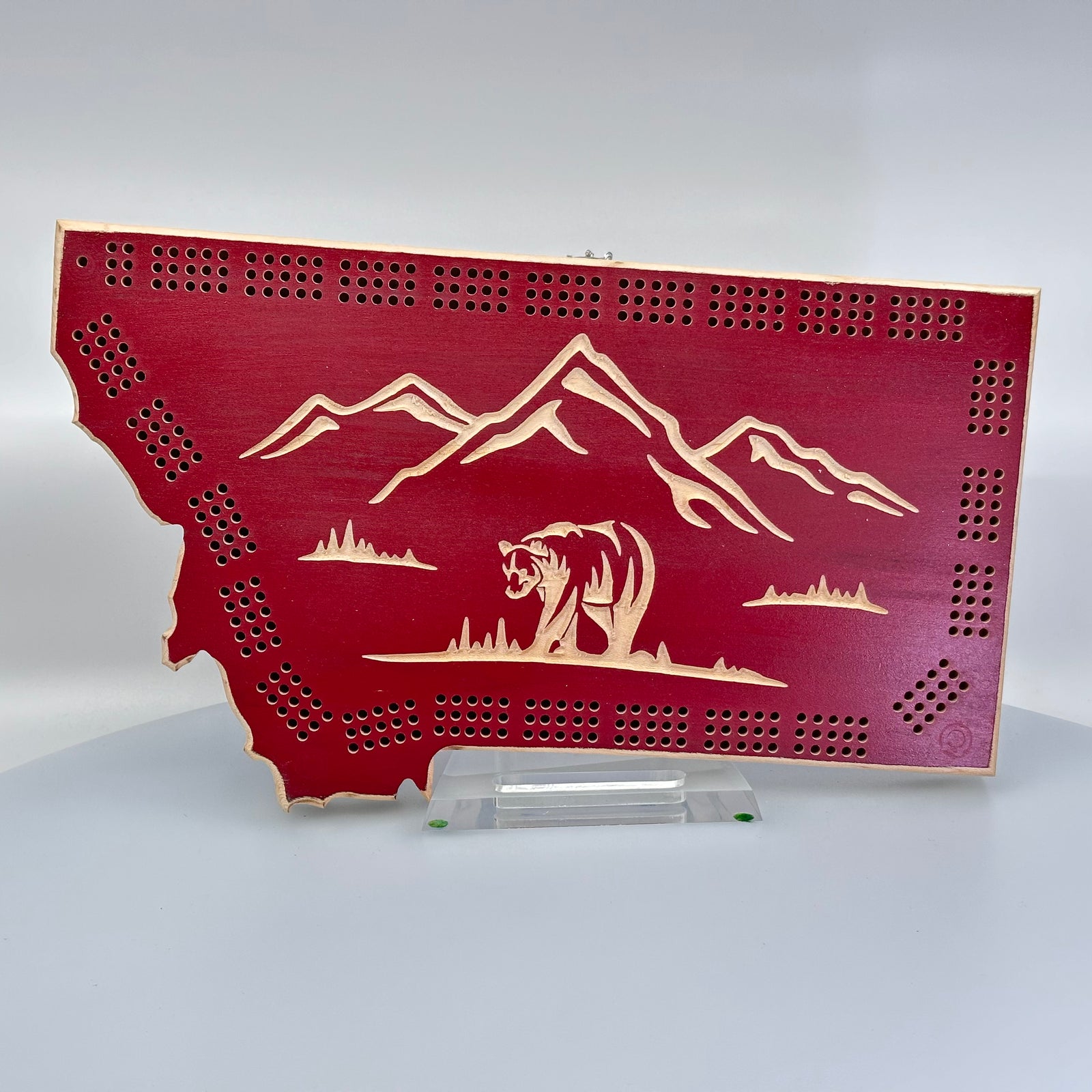 Knotty Pine Woodworks Montana Bear Cribbage Board (maroon with natural wood accents, front)--this made in Montana wood cribbage board is in the shape of Montana with sunset colors, and features a bear and mountain peaks engraved in the front.