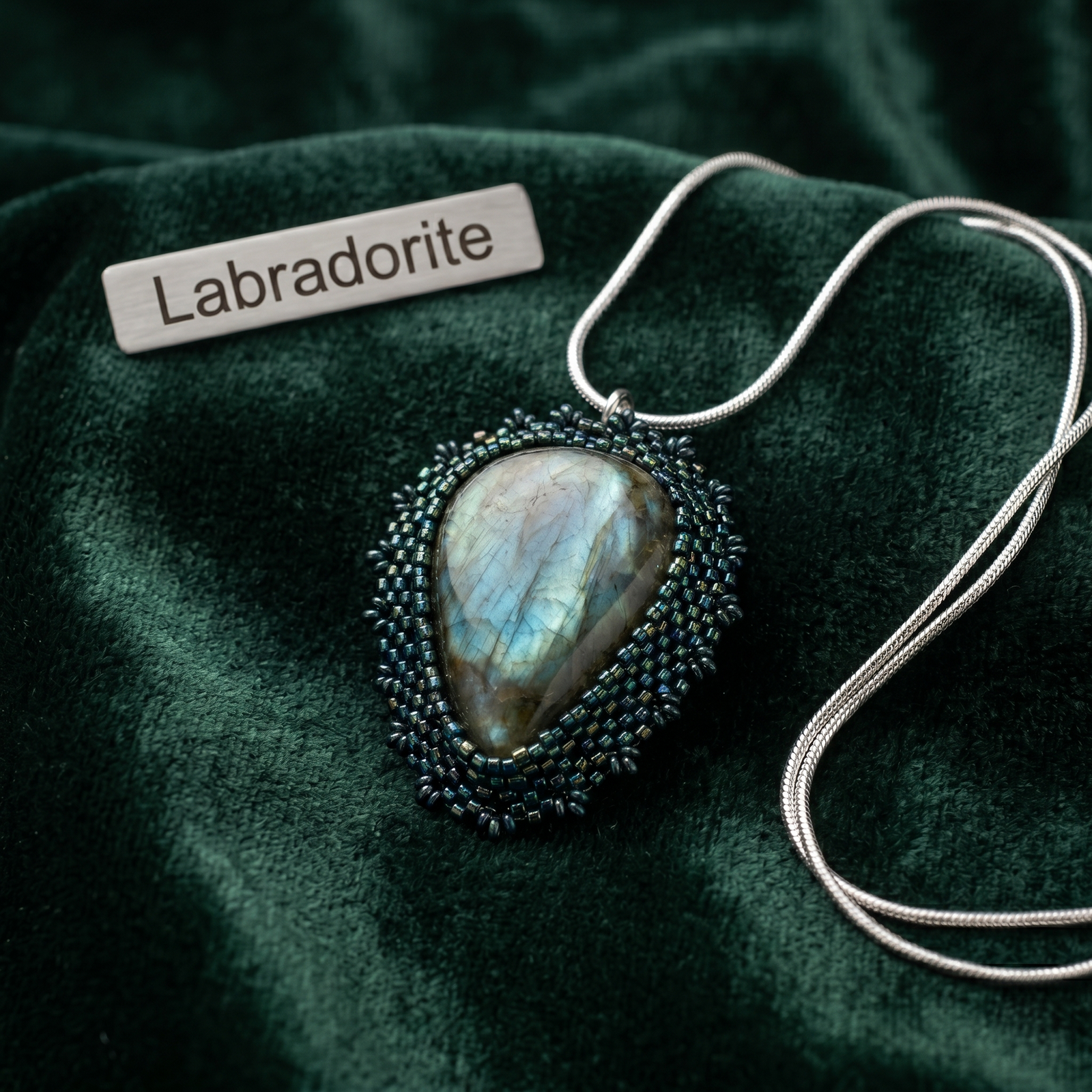 Labradorite hand beaded pendant on a green fabric background with 'Labradorite' label.