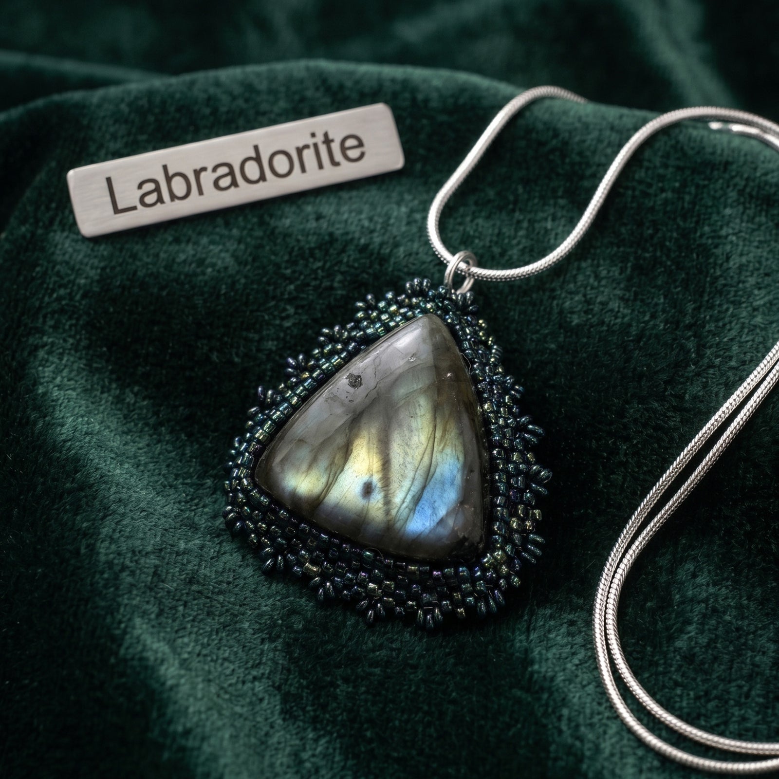 Labradorite hand beaded pendant necklace on a green fabric background with 'Labradorite' label.