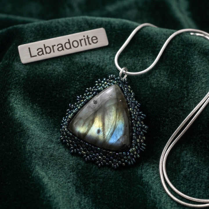 Labradorite hand beaded pendant necklace on a green fabric background with &