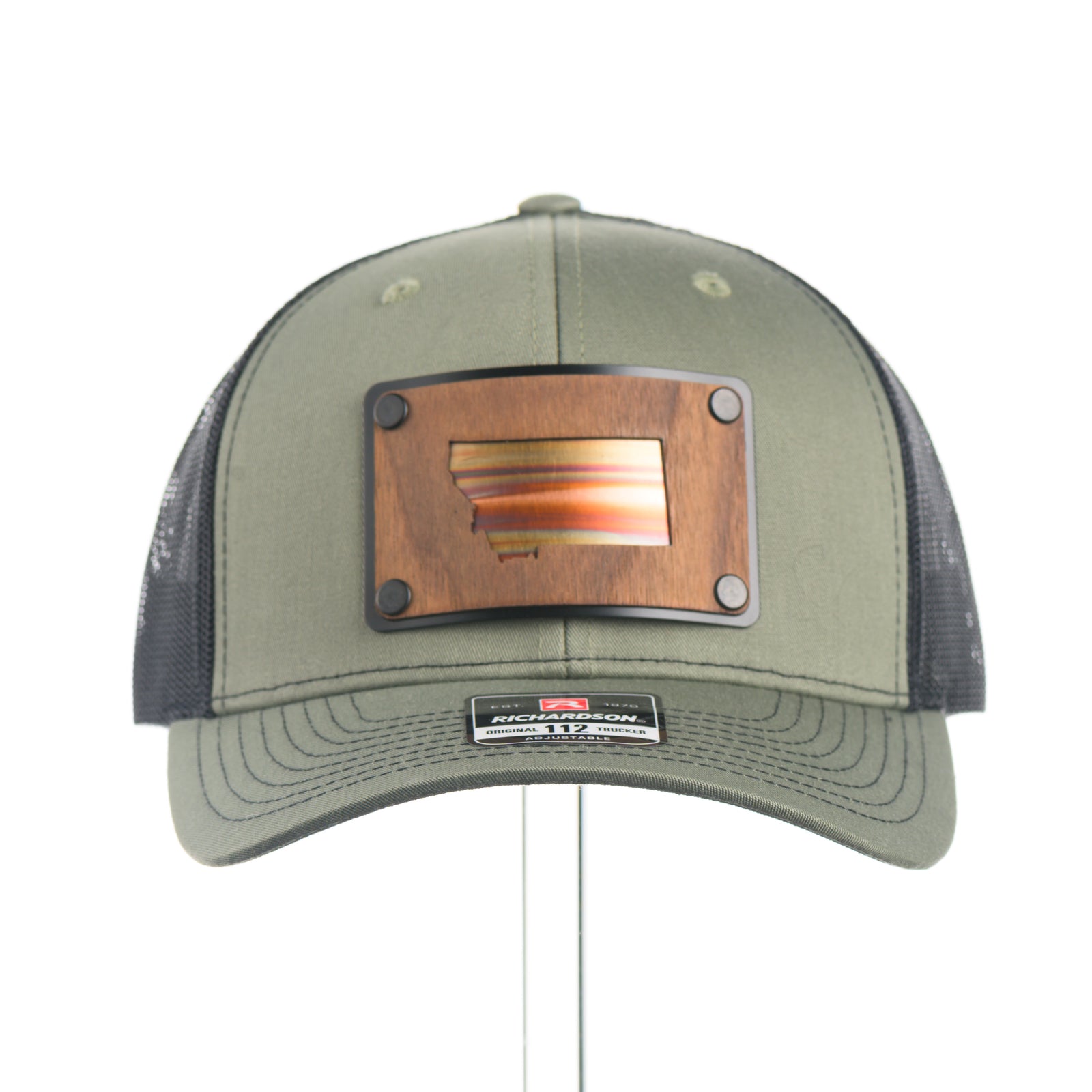 The front of a Montana Walnut Wood with Sundae Copper Patch on Richardson Trucker Hat, featuring a rectangular, real walnut wood veneer patch with a precision-cut state of Montana silhouette cutout, laminated to a black anodized metal plate, and then riveted to an olive green Richardson 112 trucker hat with black mesh—handmade in Montana, USA by Last Best Supply Co.
