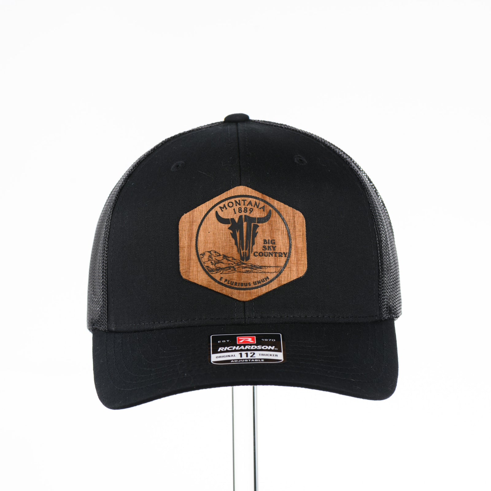 Front of a Black Montana 1889 Centennial Coin Wood Patch Trucker Hat featuring a hexagon Flexwood patch inspired by a Montana centennial quarter—handmade in Montana, USA by Last Best Supply Co.
