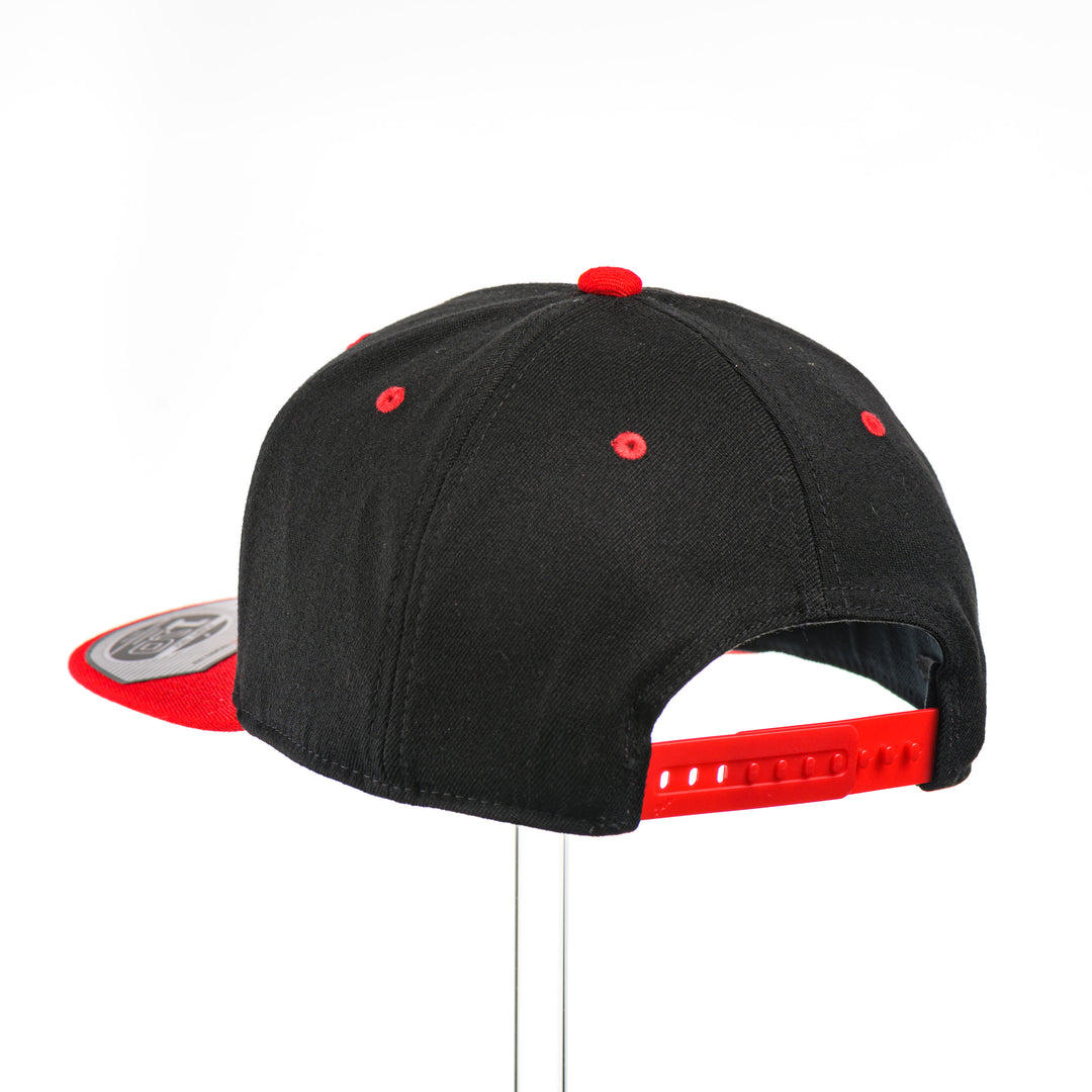The back of a Grizzly Bear w/ Lines Walnut Wood Black & Red Flat Bill Hat, featuring a hexagonal real walnut wood veneer patch with a cut-out bear silhouette and fine line details, laminated to a hexagonal red anodized aluminum plate, and riveted to a black and red Flexfit 110F flat bill hat—handmade in Montana, USA by Last Best Supply Co.