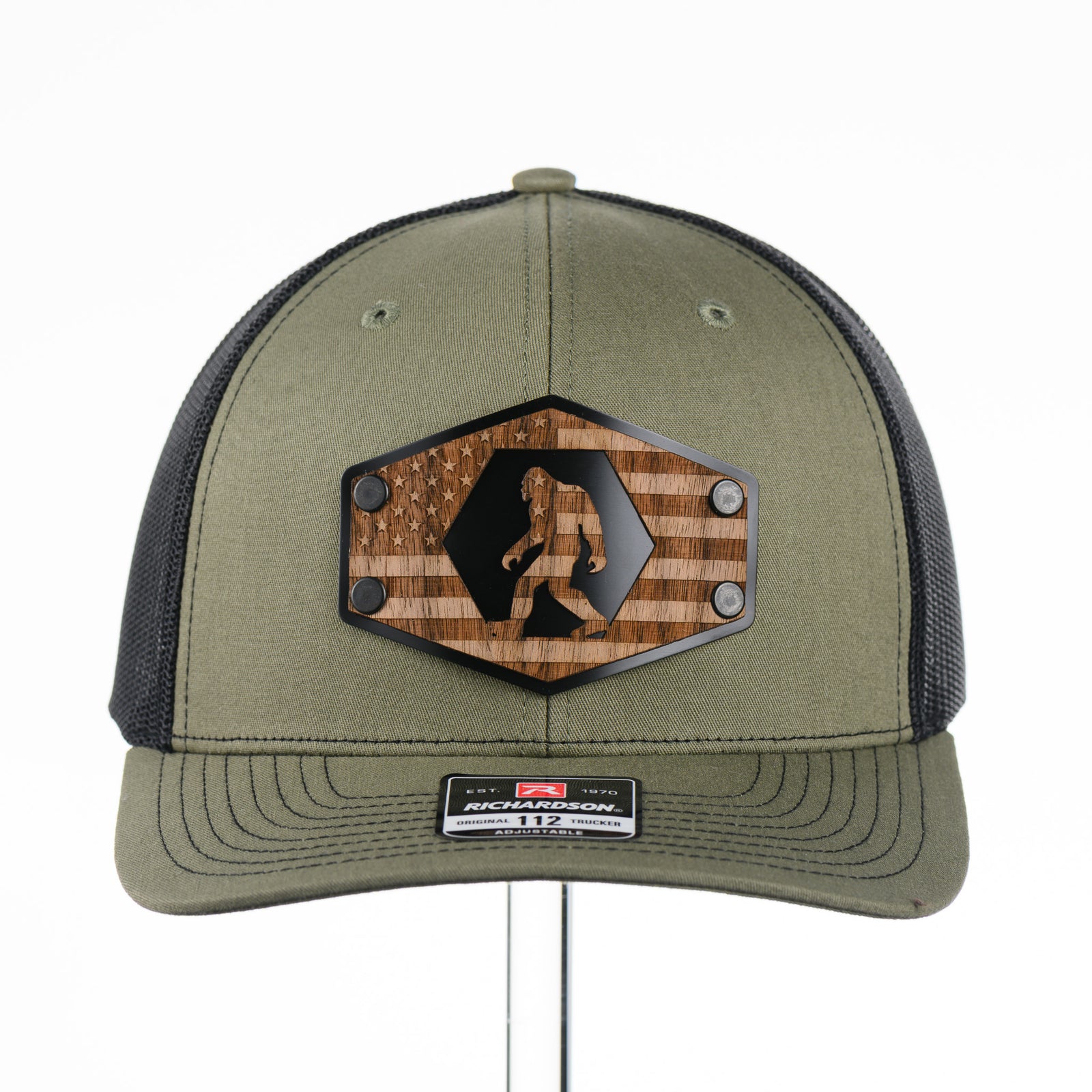 Walnut Wood Bigfoot American Flag Patch Trucker Hat featuring a real walnut wood patch laminated to a hexagon-shaped black anodized aluminum plate with an etched American flag and Bigfoot design, handmade in Montana, USA by Last Best Supply Co.