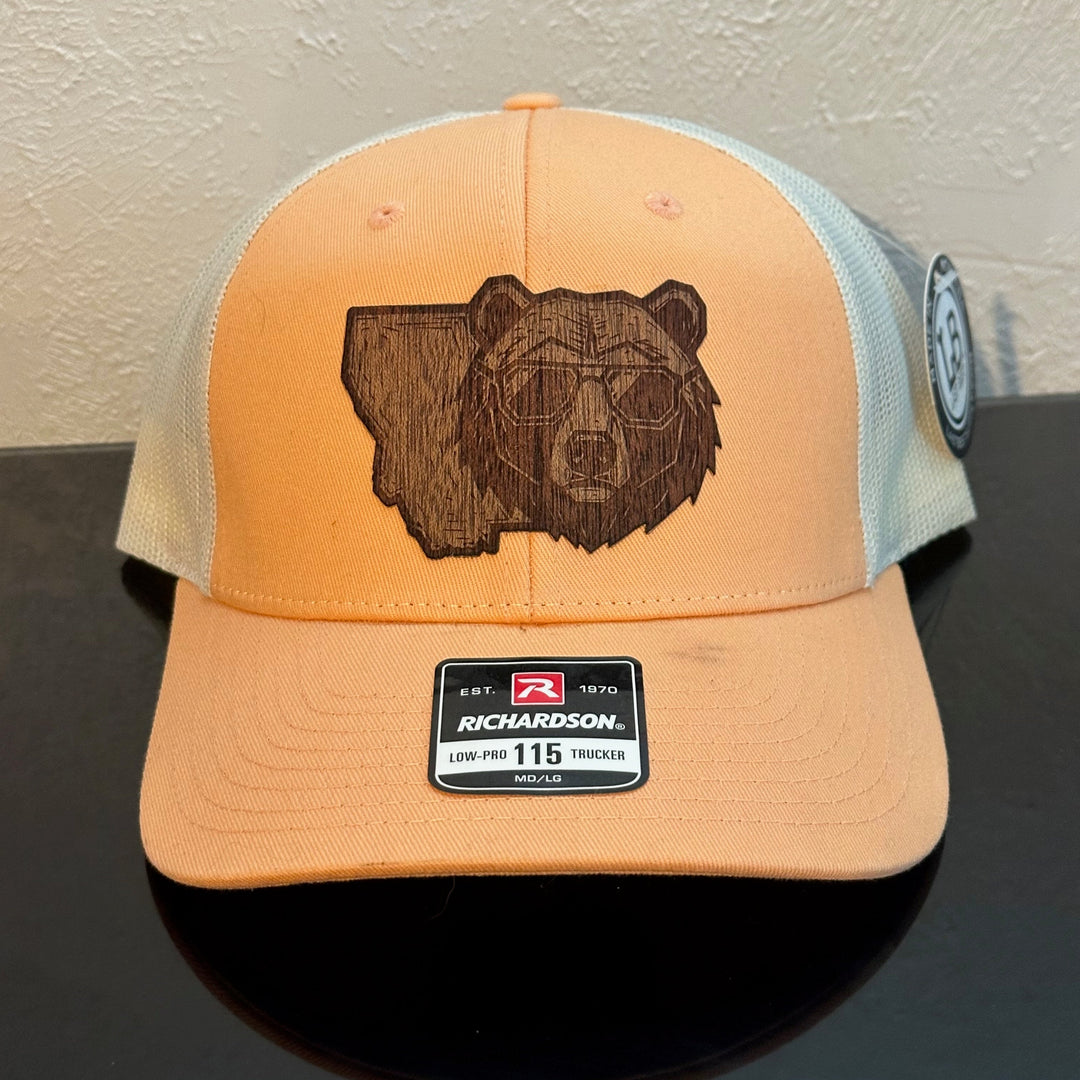 Front of a Richardson 115 Peach & Birch trucker hat decorated with a Montana Bear Mahogany Wood Patch - the head of a bear wearing sunglasses superimposed on the state of Montana - made in Montana by Last Best Supply Co.