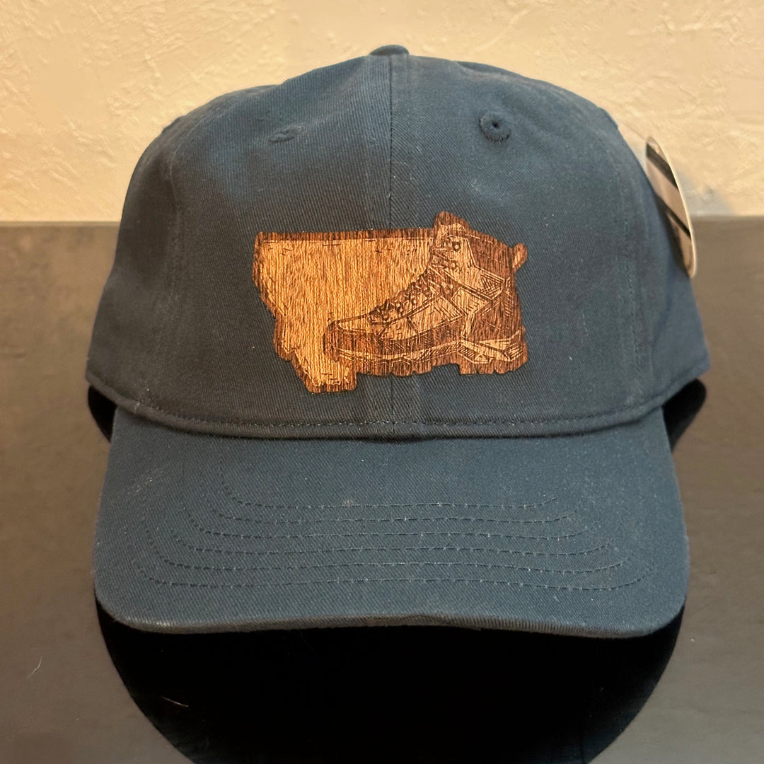 Front of an EConscious Navy 100% Cotton Unstructured Baseball Hat
decorated with a Montana Hiking Boot Mahogany Wood Patch - a sketch of a hiking boot, superimposed on the state of Montana - made in Montana by Last Best Supply Co.