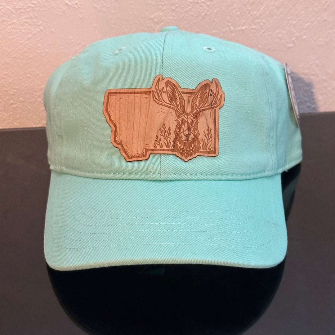 Front of an EConscious Mint Hemp Unstructured Baseball Hat decorated with a Montana Jackalope Wood Patch - a jackalope & wildflowers superimposed on the outline of Montana - made in Montana by Last Best Supply Co.