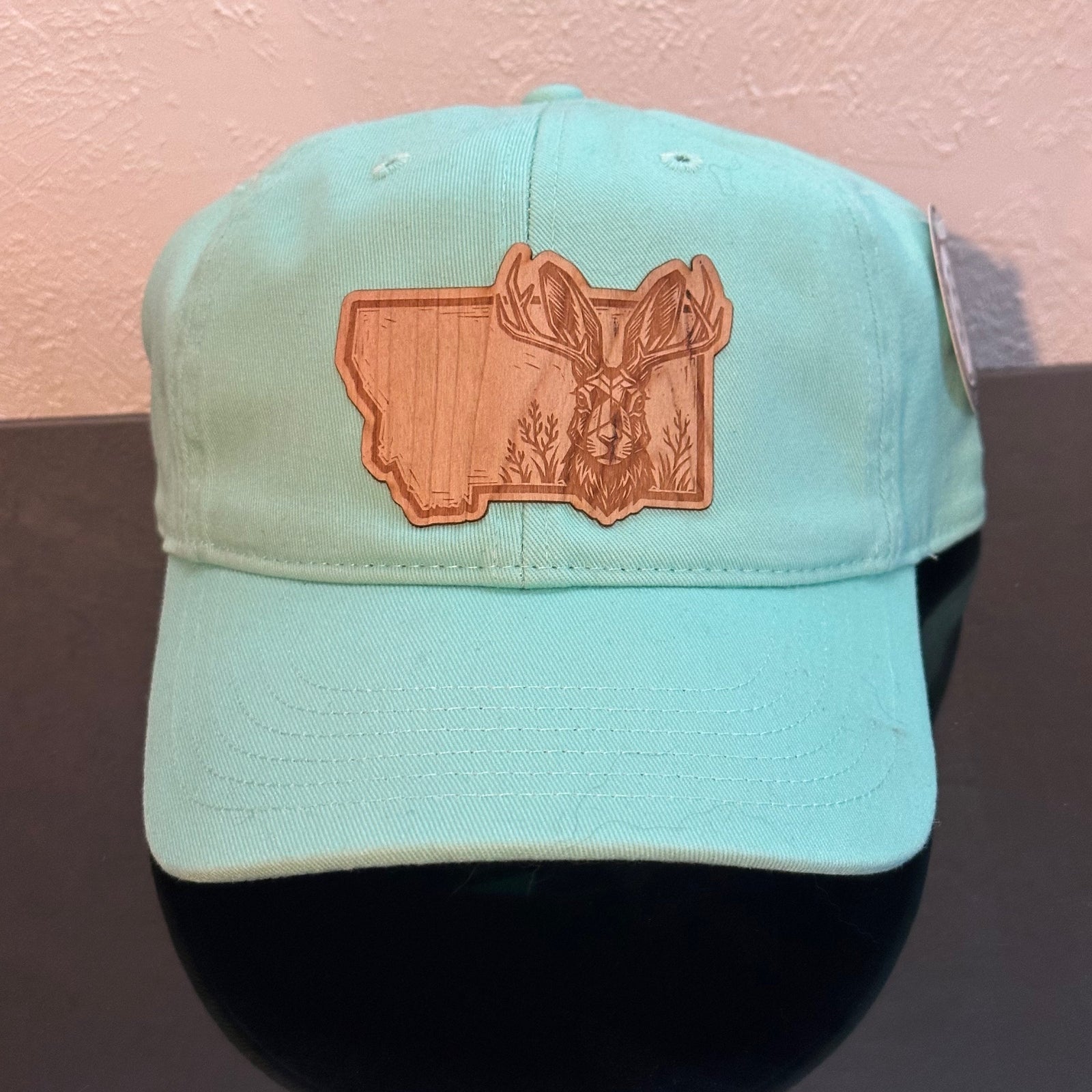Front of an EConscious Mint Hemp Unstructured Baseball Hat decorated with a Montana Jackalope Wood Patch - a jackalope & wildflowers superimposed on the outline of Montana - made in Montana by Last Best Supply Co.