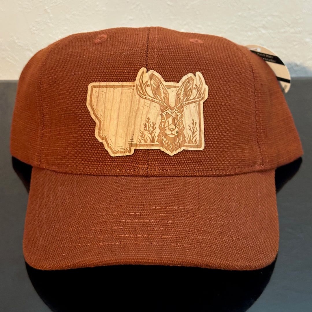 Front of an EConscious Rust Washed Hemp Unstructured Baseball Hat decorated with a Montana Jackalope Wood Patch - a jackalope & wildflowers superimposed on the outline of Montana - made in Montana by Last Best Supply Co.