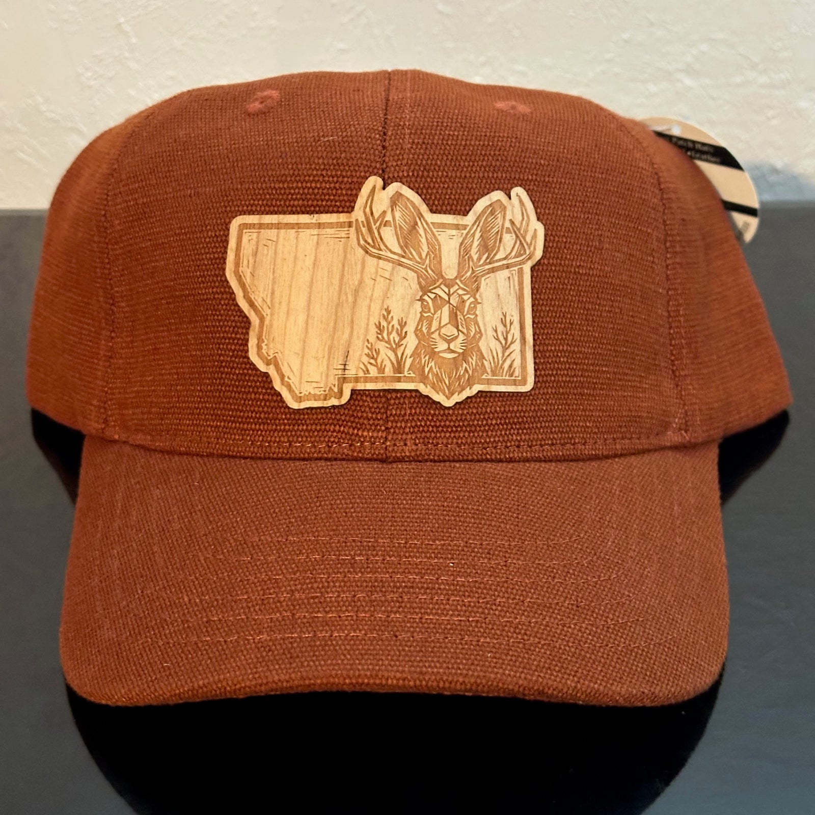 Front of an EConscious Rust Washed Hemp Unstructured Baseball Hat decorated with a Montana Jackalope Wood Patch - a jackalope & wildflowers superimposed on the outline of Montana - made in Montana by Last Best Supply Co.