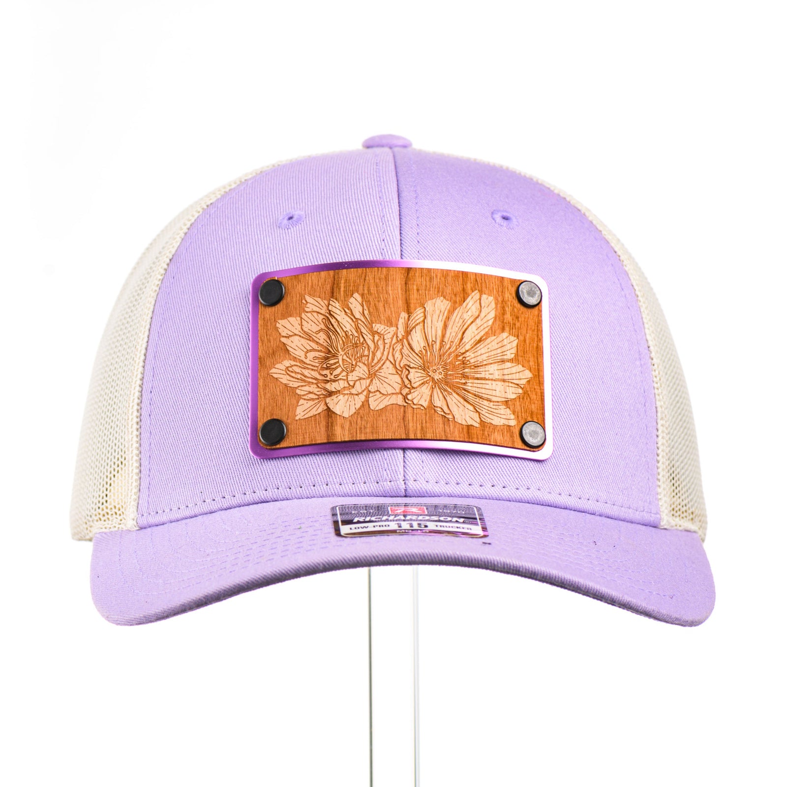 Cherry Wood Bitterroot Flower Patch Lilac & Cream Trucker Hat, featuring a real cherry wood veneer patch etched with a bitterroot flower, laminated to a light purple anodized aluminum plate and riveted to a lilac and cream trucker hat along—handmade in Montana, USA by Last Best Supply Co.