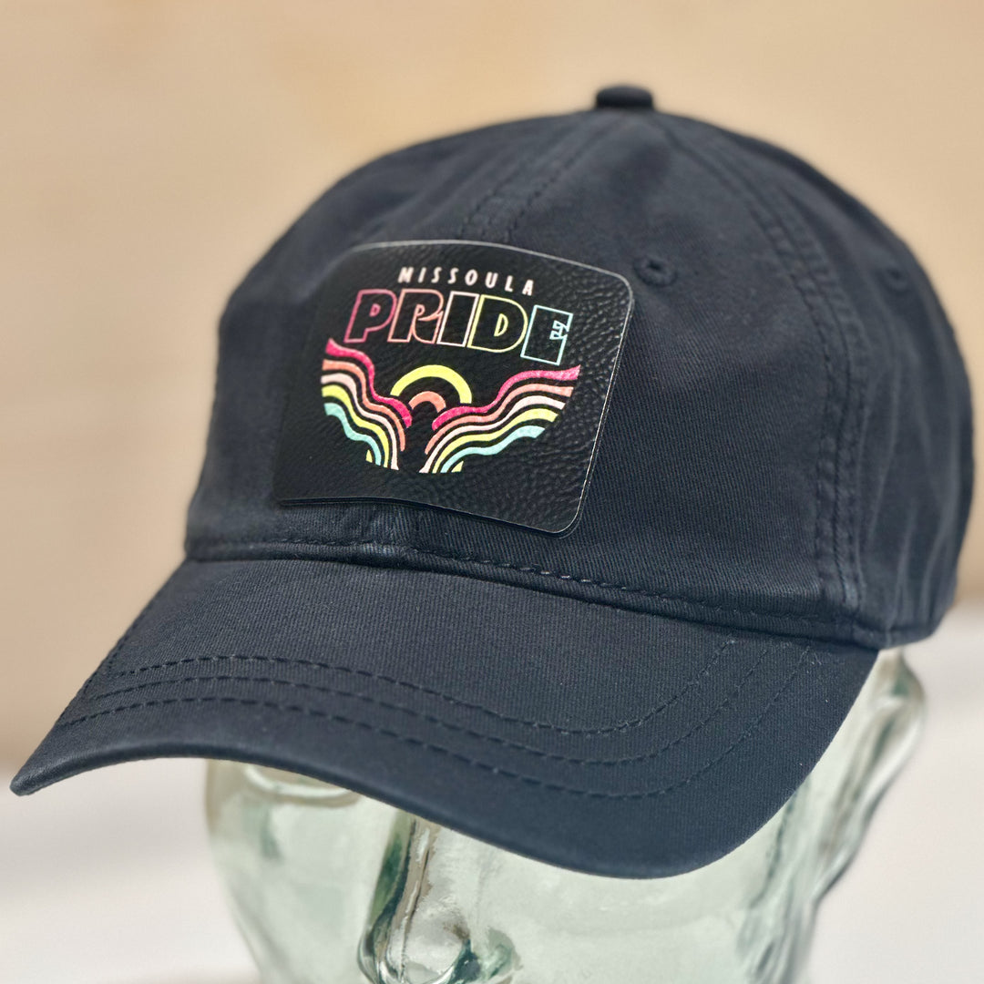 A black unstructured hat with a soft 2026 Missoula Pride portal leatherette patch