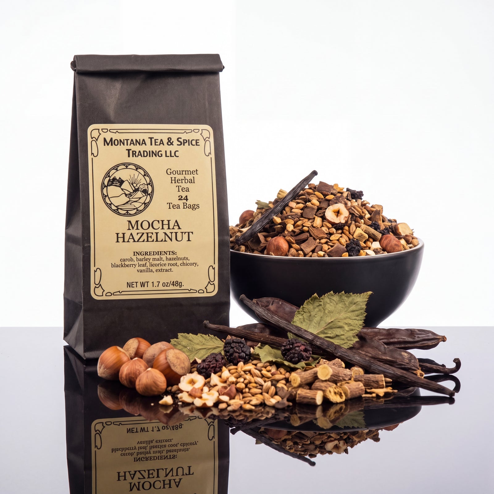 A bag of Montana Tea & Spice Trading LLC Mocha Hazelnut herbal tea stands on a reflective black surface next to a bowl filled with the tea blend and loose ingredients including hazelnuts, cinnamon sticks, vanilla beans, and dried berries.
