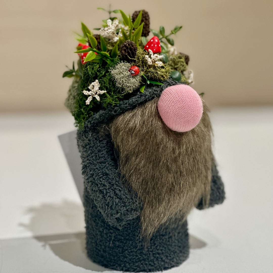 Gnome figurine with a knitted outfit and mushroom forest hat on a white surface