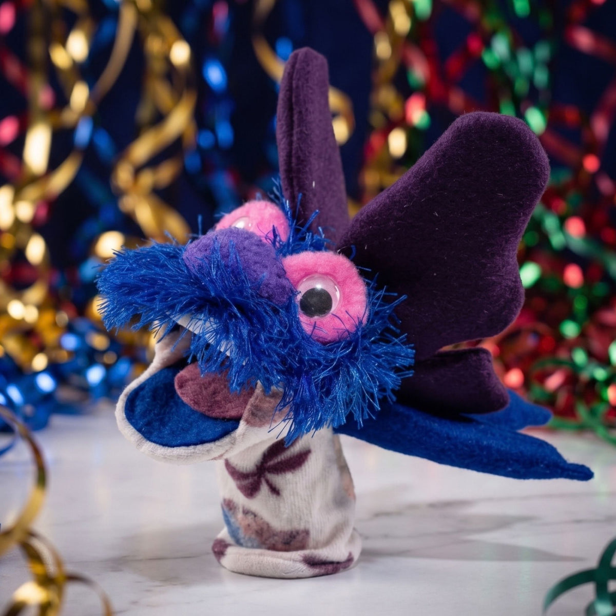 Discover Bitterroot Flutter Butter, a handcrafted Montana puppet with purple wings and blue trim. Perfect for creative play, storytelling, and gifts!