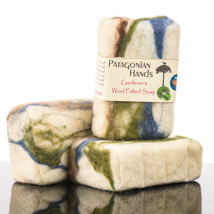 Two bars of Patagonian Hands Gardener's Wool Felted Soap with a label on a reflective surface.