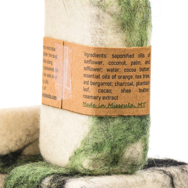 Close-up of a product with a felted bar of soap label detailing ingredients, made in Montana.