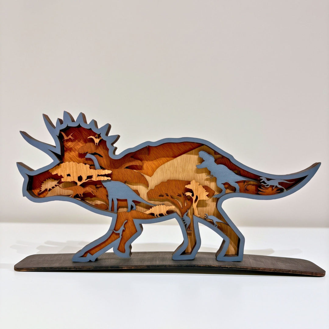 Multiple layers of natural wood are precision laser-cut and hand-assembled to form a dynamic Triceratops silhouette, revealing intricate prehistoric scenes and silhouettes hidden within every tier. Mounted on a sturdy display base, this freestanding wooden sculpture