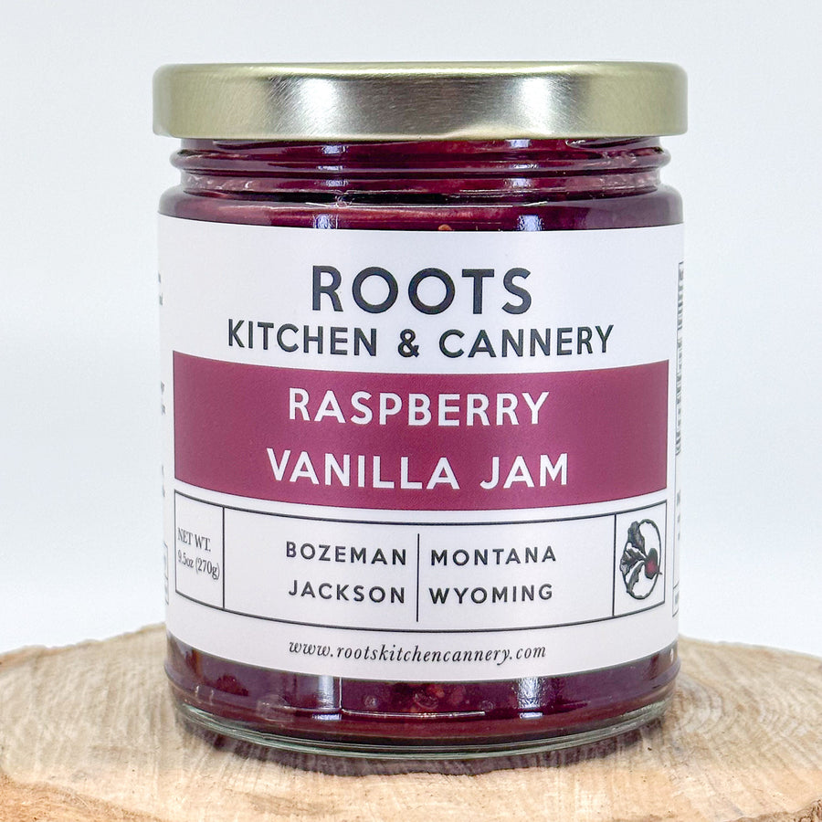 A 9.5 oz jar of raspberry vanilla jam, with a modern, white and raspberry colored label. By Roots Kitchen & Cannery
