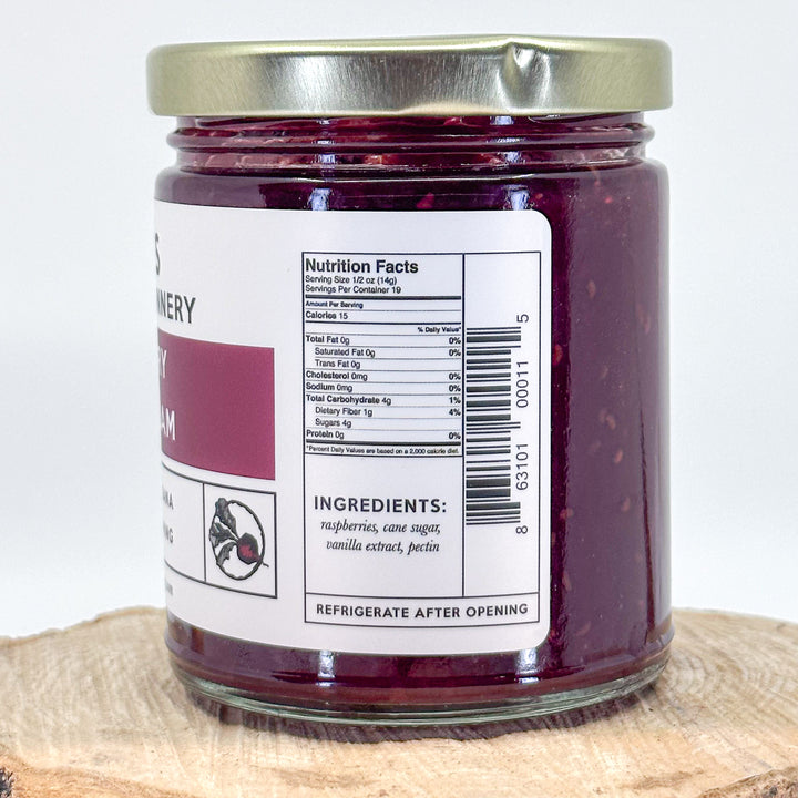 The side of a jar of raspberry vanilla jam that has the nutrition facts and the ingredients. The ingredients are raspberries, cane, sugar, vanilla extract, pectin