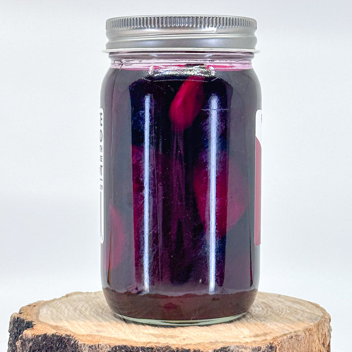 The back of a jar of pickled beets and garlic. The beets are soaking in a deep purple red brine.