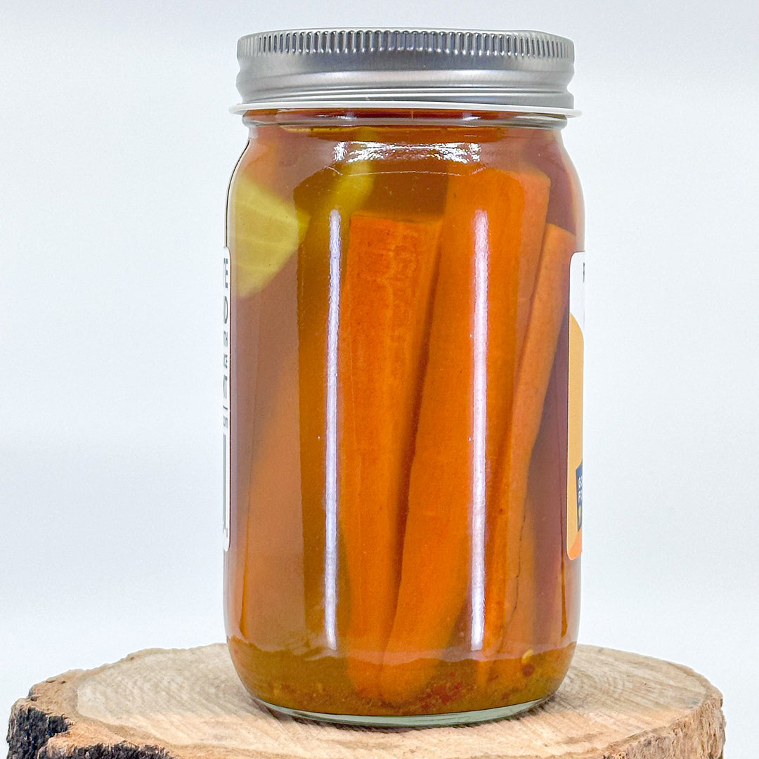 The back of a jar of curried carrot pickles, showing the carrots in a the pickling liquid
