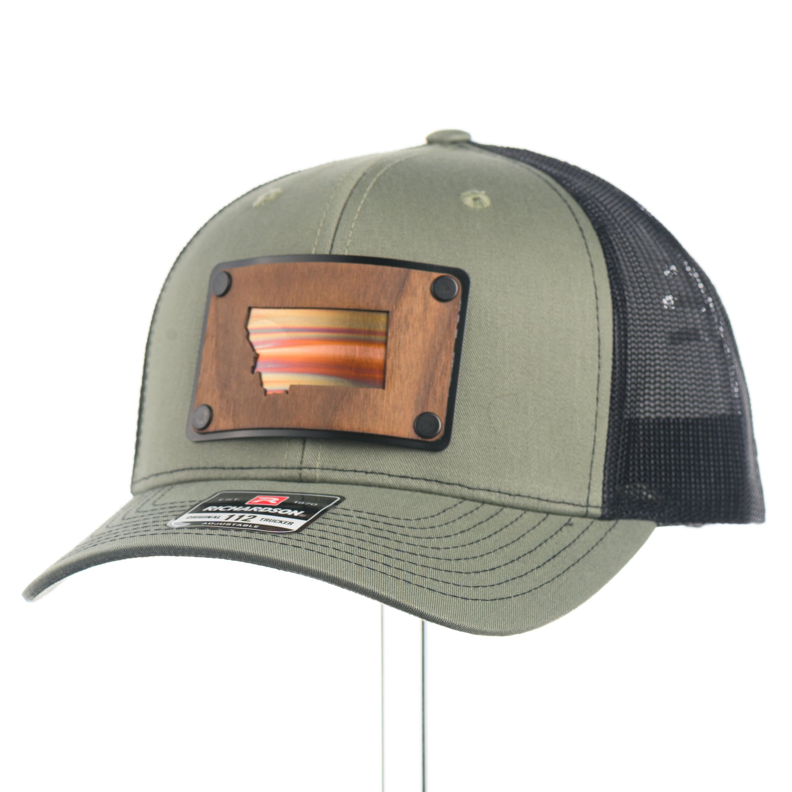 The 3 quarter view of a Montana Walnut Wood with Sundae Copper Patch on Richardson Trucker Hat, featuring a rectangular, real walnut wood veneer patch with a precision-cut state of Montana silhouette cutout, laminated to a black anodized metal plate, and then riveted to an olive green Richardson 112 trucker hat with black mesh—handmade in Montana, USA by Last Best Supply Co.