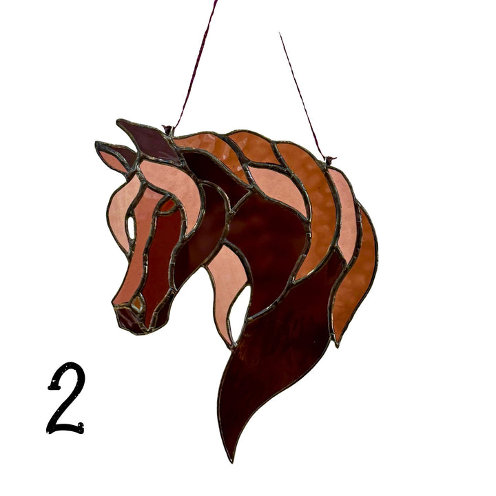 A stained glass horse head hanging ornament in shades of brown, terracotta, and dark burgundy with black metal outlines, shown against a plain white background with a black number 2 in the lower left.