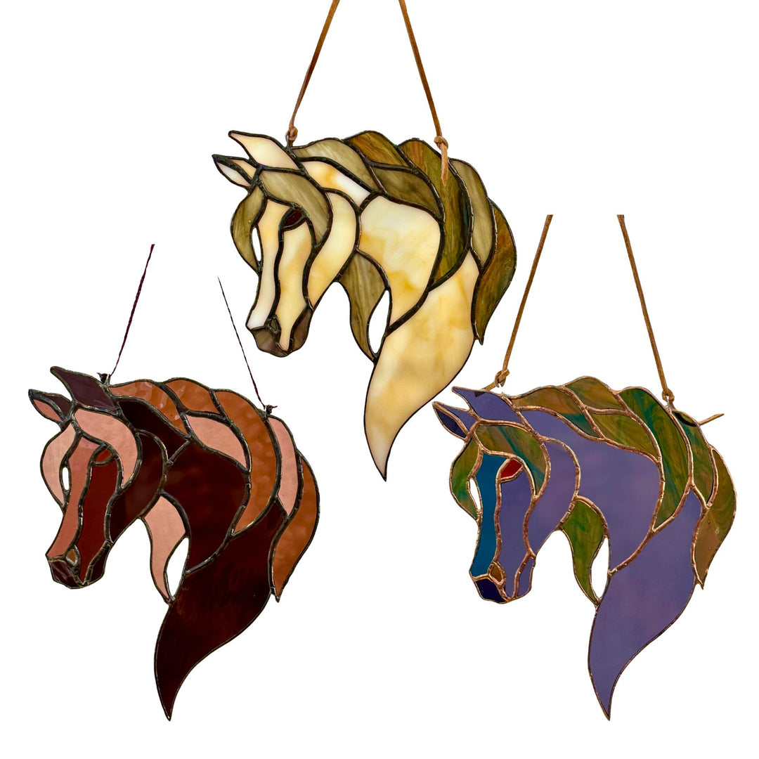 Three stained glass horse head hanging stained glass ornaments in different colors, shown against a plain white background.