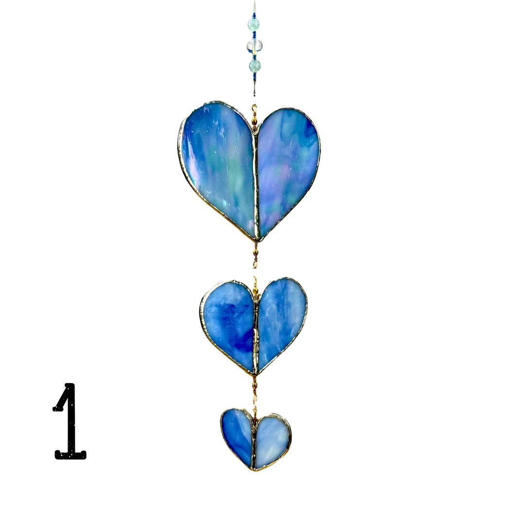 A suncatcher with three blue marbled glass heart panels with a light blue beaded cord.
