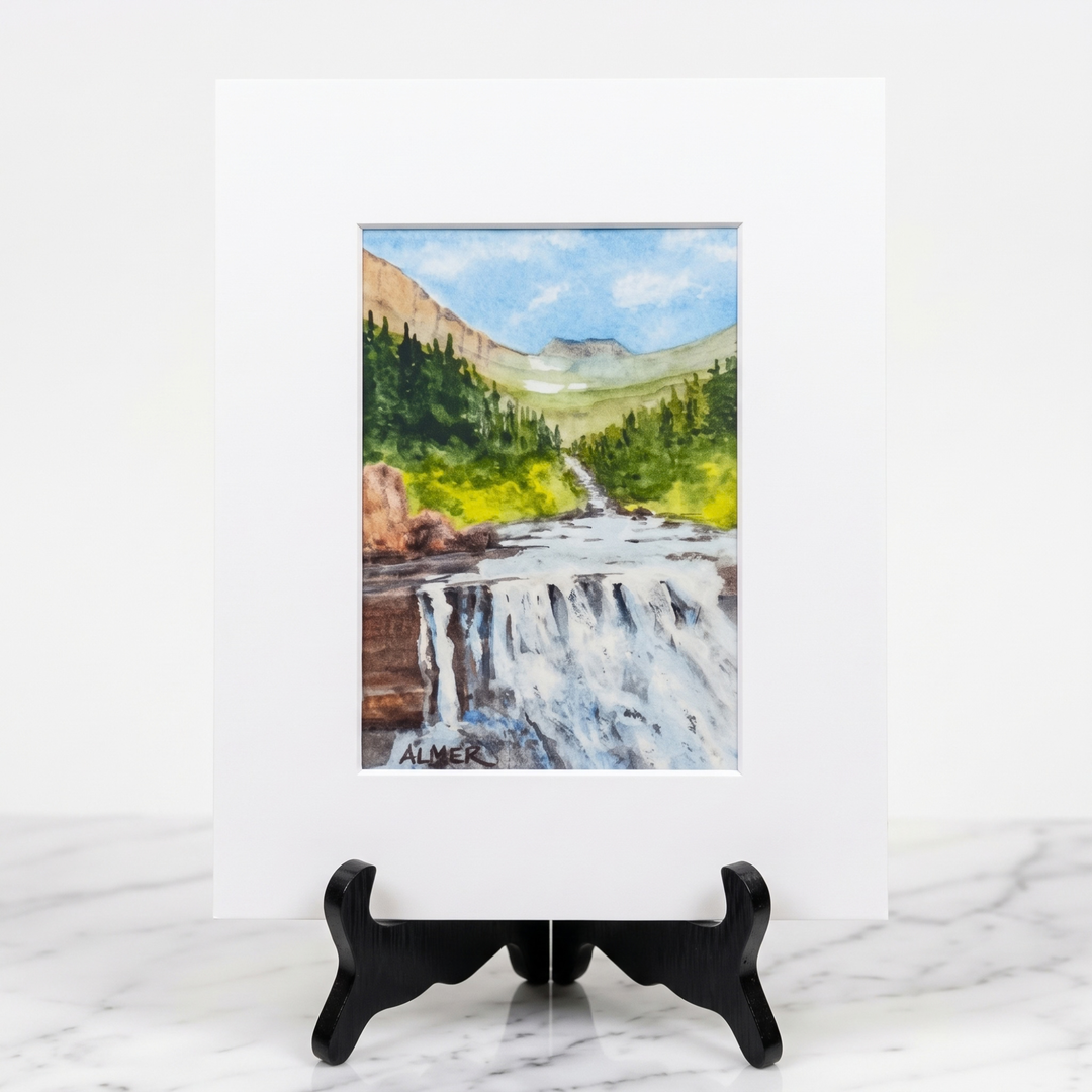 Experience Glacier National Park’s beauty with the 5x7 Lunch Creek Falls Matted Print by Stark Mountain Studio, reproducing a Bobbe Almer artwork.