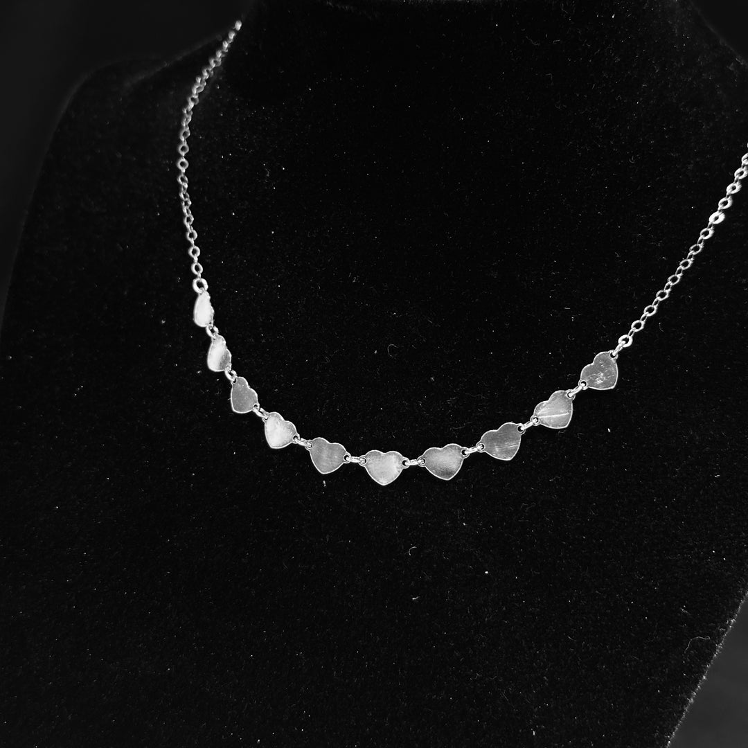 A strand of sterling silver hearts necklace displayed on a black background
