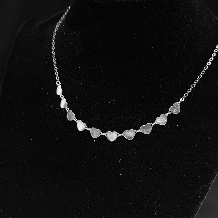 A strand of sterling silver hearts necklace displayed on a black background