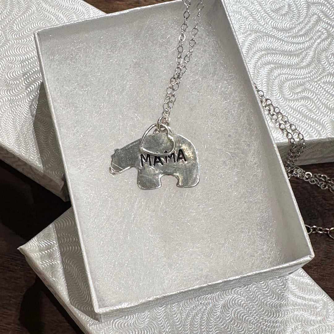 A silver necklace with a bear-shaped pendant engraved with the word &