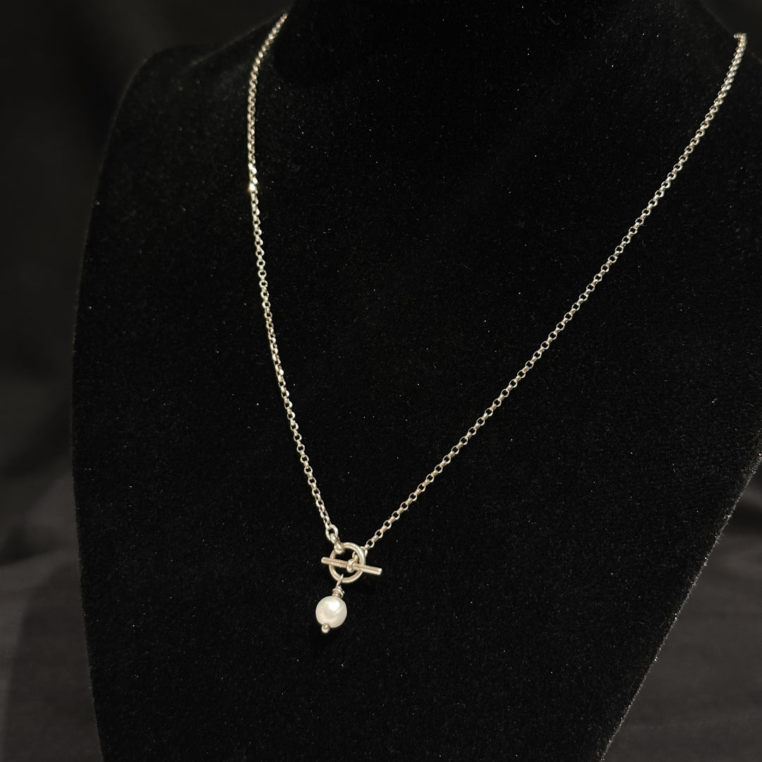 A sterling silver and pearl tole necklace on a black background