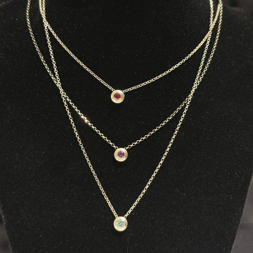Three layered birthstone necklaces with colored cubic zirconia in sterling silver on a black background made in Montana