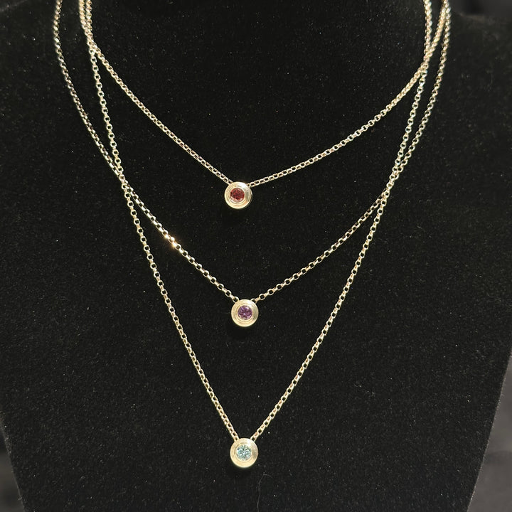 Three layered birthstone necklaces with colored cubic zirconia in sterling silver on a black background made in Montana