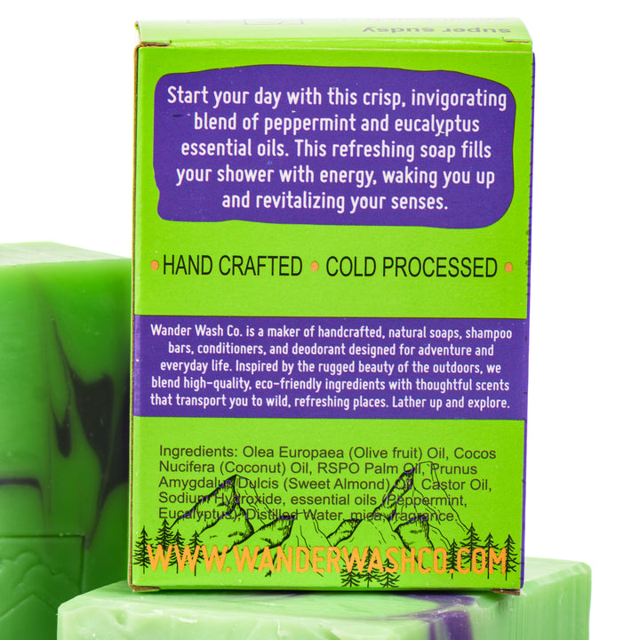 Display of three 5.25 oz bars of Panda Breath Mints Bar Soap, Natural Cold Process Soap (eucalyptus, mint)—one in the box and two out of the box--made in Montana by Wander Wash Co, focused on back (ingredients list) against a white background