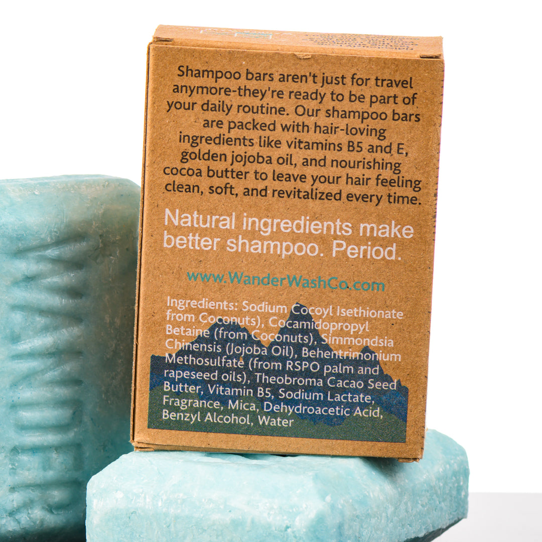 Display of three 4.5 oz bars of This Doesn’t Float Shampoo Bar (bergamot, fresh water)—one in the box and two out of the box--made in Montana by Wander Wash Co, focused on back (ingredients list) against a white background