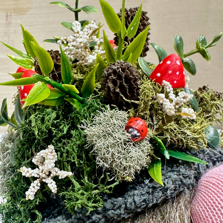 a gnome hat with a Decorative arrangement with red mushrooms, green leaves, and moss on a neutral background