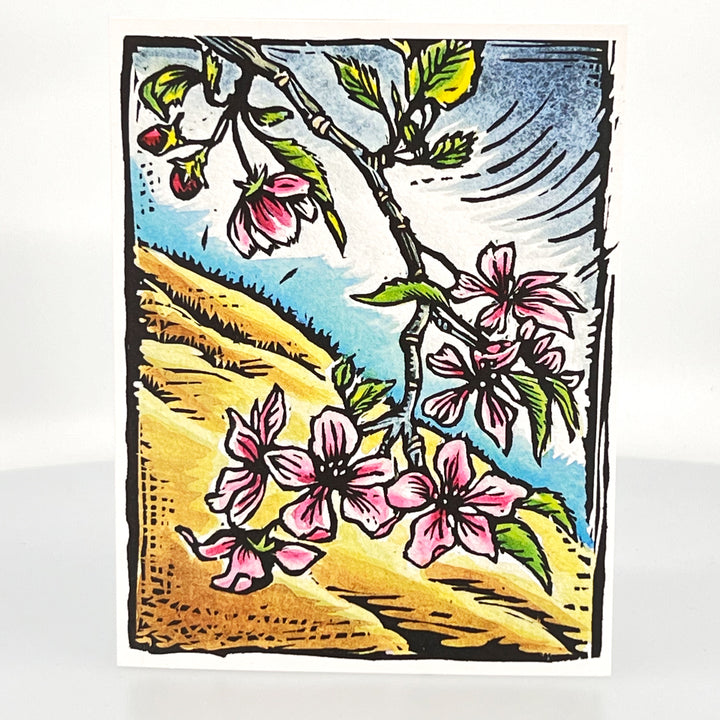 A picture of a greeting card with a woodcut of apple blossoms on the front
