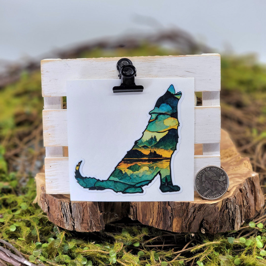 A vinyl sticker depicting a colorful wolf silhouette filled with various tones of blue and green, presented on a wooden display stand.